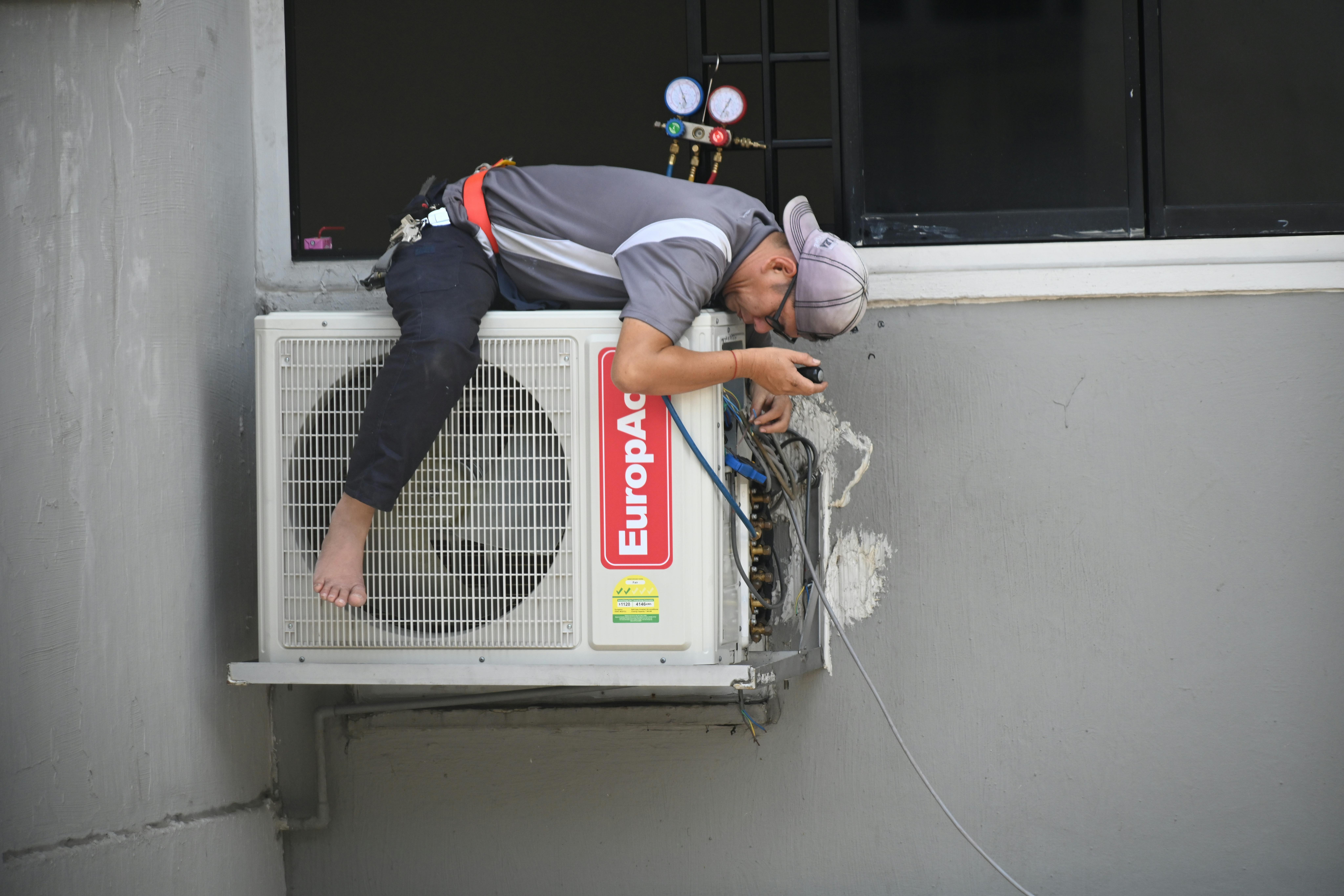 HVAC tehničar leži na klimi i popravlja je
